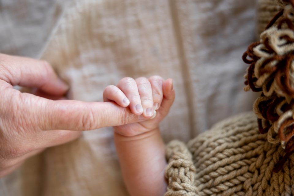 Bir yetişkinin parmağını tutan bebek eli
